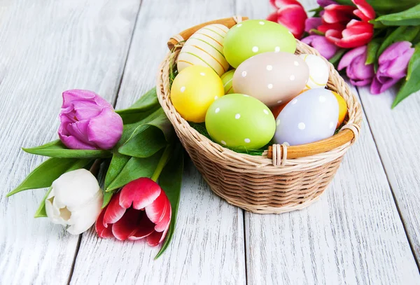 Basket with easter eggs and tulips — Stock Photo, Image