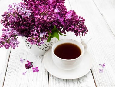 Fincan çay ve eflatun çiçekler
