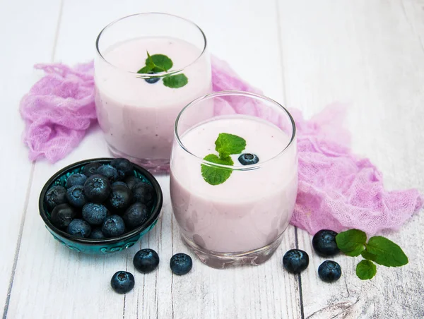 Óculos com iogurte de mirtilo em uma mesa — Fotografia de Stock