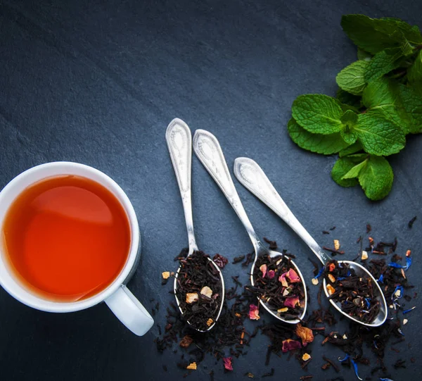 Tekopp och sortiment av torr te i skedar — Stockfoto