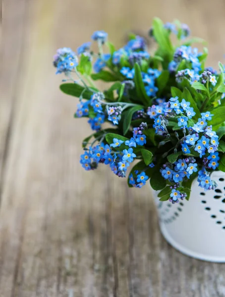 Forget-me-not flowers in small metal bucket on old table