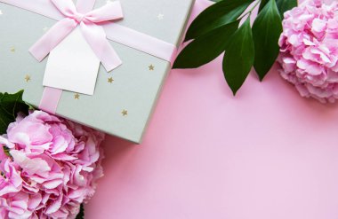 Pembe arka planda pembe renkli ortanca çiçekleri ve gümüş hediye kutusu olan bir tebrik kartı için şenlikli bir arka plan.