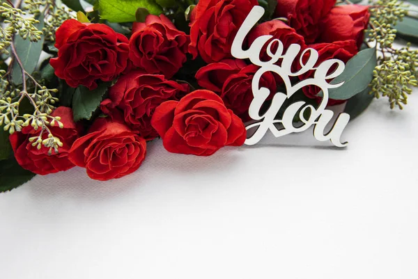 Red roses with eucalyptus on white background