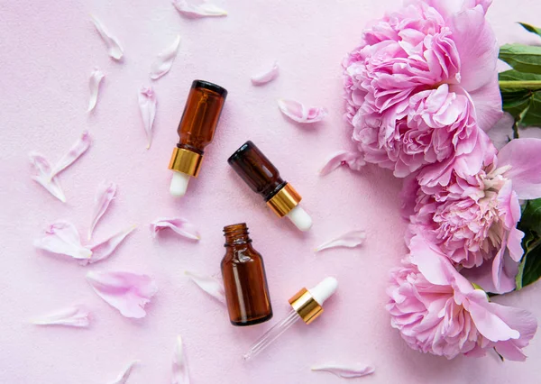 Aromatherapy essentials oils and pink peonies — Stock Photo, Image