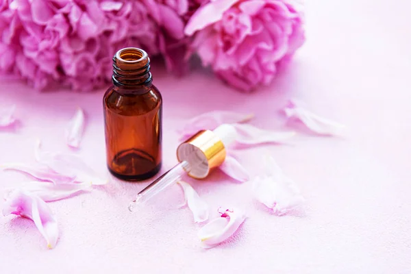 Aromatherapy essentials oils and pink peonies — Stock Photo, Image