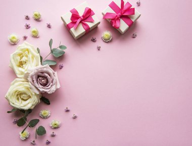 Çiçekler ve hediye kutuları pembe arka planda