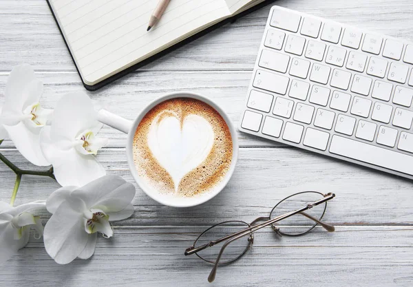 En kopp kaffe med hjertemønster på et bord. – stockfoto