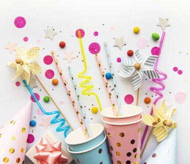 Beyaz arka planda doğum günü partisi şapkaları, kağıt kamışları, şeker ve konfetiler