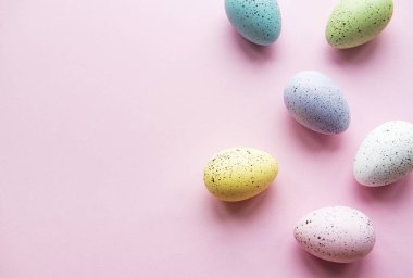 Paskalya tatili geçmişi. Pastel pembe arka planda renkli Paskalya yumurtaları. Düz yatış, üst görünüm.