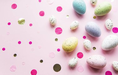 Paskalya tatili geçmişi. Pastel pembe arka planda renkli Paskalya yumurtaları. Düz yatış, üst görünüm.