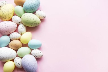 Paskalya tatili geçmişi. Pastel pembe arka planda renkli Paskalya yumurtaları. Düz yatış, üst görünüm.