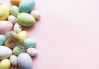 Paskalya tatili geçmişi. Pastel pembe arka planda renkli Paskalya yumurtaları. Düz yatış, üst görünüm.