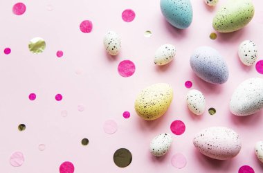 Paskalya tatili geçmişi. Pastel pembe arka planda renkli Paskalya yumurtaları. Düz yatış, üst görünüm.