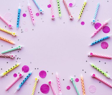 Mutlu yıllar, konfeti ve pembe arka planda çok renkli mumlar. düz yatış, üst görünüm