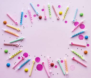 Mutlu yıllar, konfeti ve pembe arka planda çok renkli mumlar. düz yatış, üst görünüm