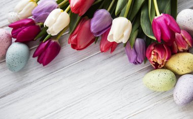 Beyaz ahşap arka planda bahar laleleri ve Paskalya yumurtaları