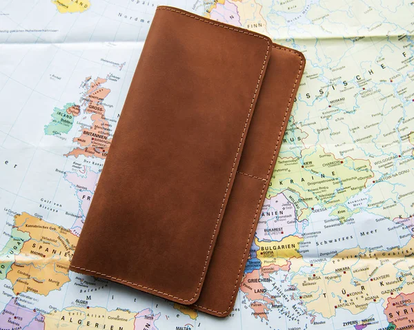 Brown leather travel organizer on a map background. Flat lay, top view. Travel concept.