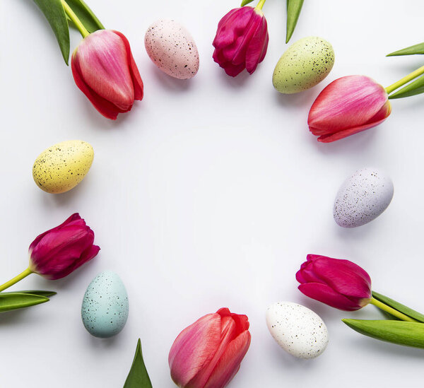 Decorative easter eggs and tulips arranged in circle. White background. Holiday decorations, Easter concept background. Top view, flat lay. 