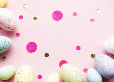 Pastel pembe arka planda renkli Paskalya yumurtaları. Paskalya tatili konsepti, düz konum, üst manzara.