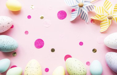 Pastel pembe arka planda renkli Paskalya yumurtaları. Paskalya tatili konsepti, düz konum, üst manzara.