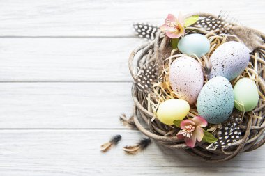 Beyaz ahşap arka planda renkli yumurtaları olan Paskalya arkaplanı. Kopyalama alanı olan üst görünüm