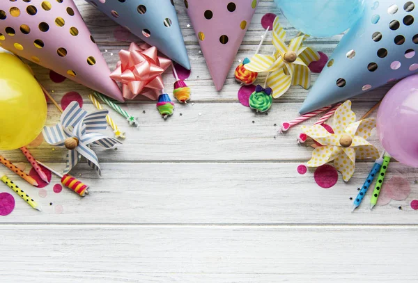 Happy birthday or party background.  Flat Lay wtih birthday hats, confetti and ribbons on white wooden background. Top View.  Copy space.