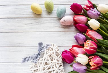 Beyaz ahşap arka planda bahar laleleri ve Paskalya yumurtaları