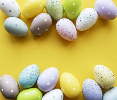 Paskalya tebrik kartı. Sarı arka planda renkli paskalya yumurtaları ve mesaj için yer. Üst manzara, düz uzanma.