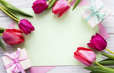 Bahar lale çiçekleri, hediye kutusu ve yukarıdan düz bir şekilde eski beyaz masadaki kağıt kart. Kadınlar ya da Anneler Günü için Selamlama.