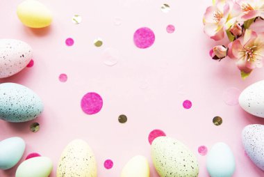 Pastel pembe arka planda renkli Paskalya yumurtaları. Paskalya tatili konsepti, düz konum, üst manzara.
