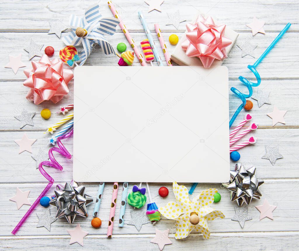 Happy birthday or party background.  Flat Lay wtih birthday hats, confetti, greeting card  and ribbons on white wooden background. Top View.  Copy space.