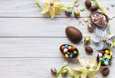 Beyaz ahşap arka planda renkli ve çikolatalı yumurtaları olan Paskalya kompozisyonu, yazı için boşluk. Üst manzara, düz uzanma. 