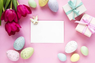 Tebrik kartı. Bahar lale çiçekleri, paskalya yumurtaları ve pastel pembe arka planda hediye kutusu..