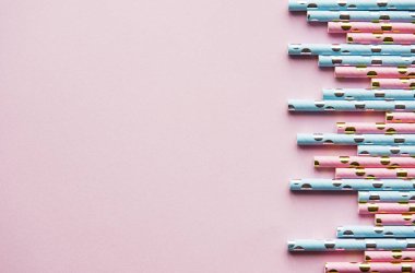 Parti için benekli pipetleri pembe arka planda fotokopi çekerek içmek. Yaz kokteylleri için renkli, tek kullanımlık, çevre dostu pipetlerin üst görüntüsü..