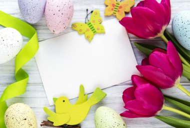 Tebrik kartı. Bahar lale çiçekleri, paskalya yumurtaları ve beyaz ahşap arka plandaki süslemeler düz bir şekilde seriliyordu..