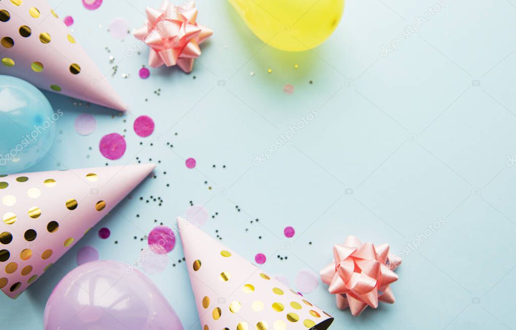 Happy birthday or party background.  Flat Lay wtih birthday hats, confetti and ribbons on blue background. Top View.  Copy space.