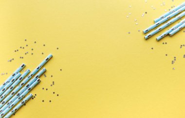 Parti için pipet içmek ve gümüş yıldızlı konfeti sarı arka planda fotokopi alanı ile. Yaz kokteylleri için renkli, tek kullanımlık, çevre dostu pipetlerin üst görüntüsü..