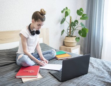Liseli kız evde dizüstü bilgisayar kullanarak ders çalışıyor. Evde kal. Çevrimiçi eğitim, ev eğitimi, karantina kavramı.