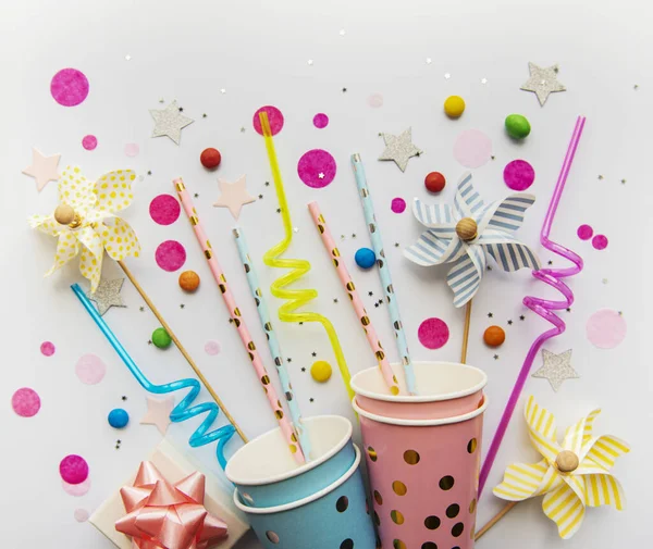 Birthday party caps,  paper straws, candy and confetti on white background