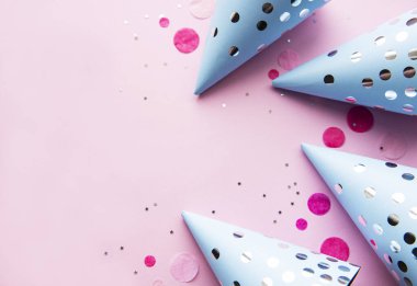 Mutlu yıllar ya da parti geçmişi. Doğum günü şapkaları ve pembe arka planda konfetileri olan düz yatış. Üst Manzara. Boşluğu kopyala.