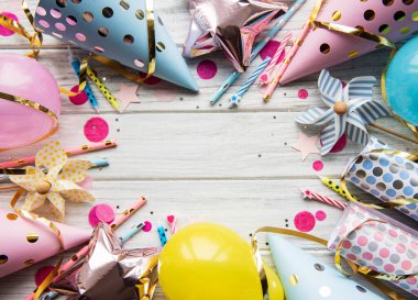 Mutlu yıllar ya da parti geçmişi. Doğum günü şapkaları, konfeti ve beyaz ahşap arka planda kurdeleler. Üst Manzara. Boşluğu kopyala.