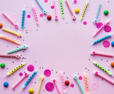 Mutlu yıllar, konfeti ve pembe arka planda çok renkli mumlar. düz yatış, üst görünüm