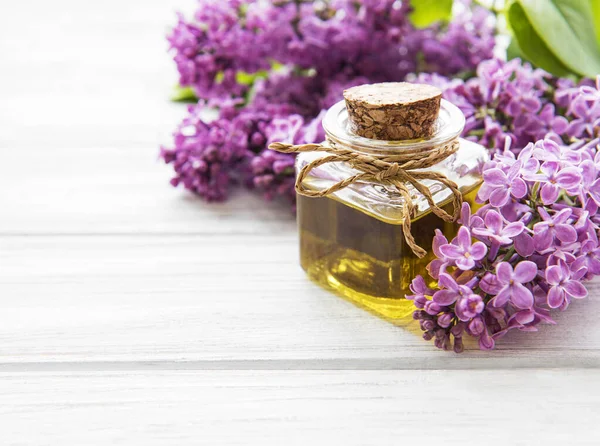 Spa oil with lilac flowers. Bottle with aroma oil  and lilac flowers on wooden background.