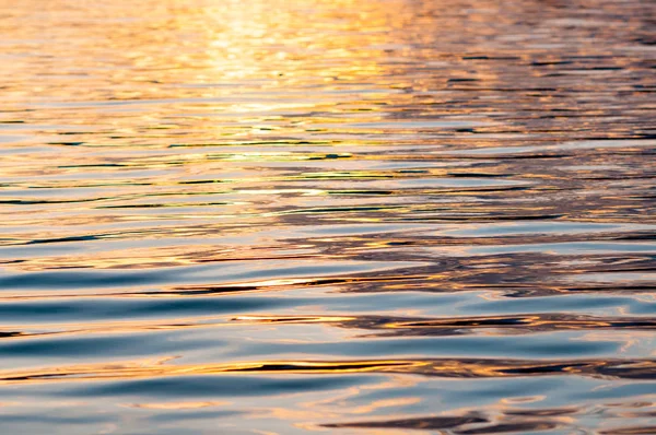 Sessiz, sakin su yüzeyi ile dalgaların gün batımında