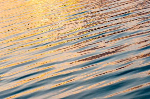 Sessiz, sakin su yüzeyi ile dalgaların gün batımında