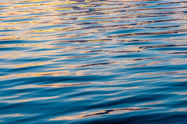 Sessiz, sakin su yüzeyi ile dalgaların gün batımında