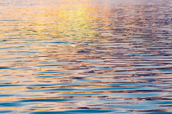 Sessiz, sakin su yüzeyi ile dalgaların gün batımında