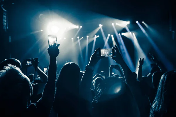 Gente en la multitud en un concierto con teléfonos inteligentes en las manos — Foto de Stock