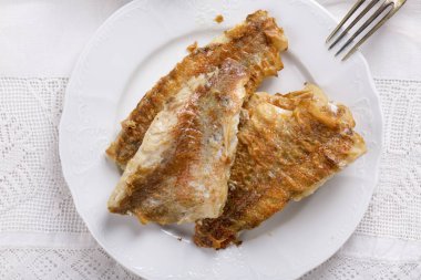 Kızarmış balık fileto beyaz bir plaka üzerinde yükseldi.. 