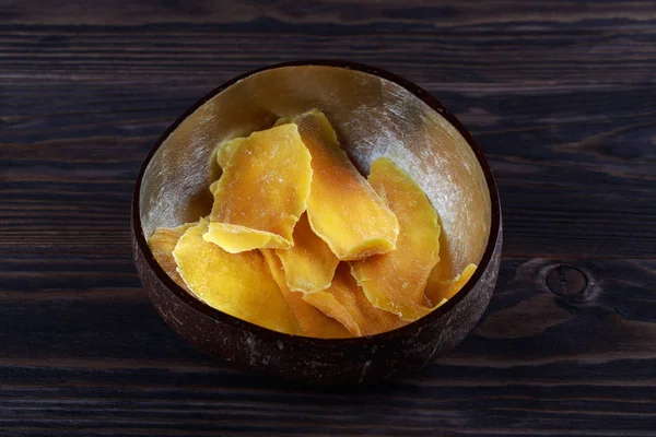 Tranches de mangue déshydratées dans un bol en bois sur fond sombre . — Photo